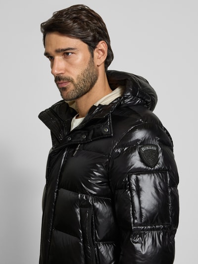 Männermodel trägt schwarze Steppjacke mit Kapuze und Eingrifftaschen Modell 'ALDRICH' von Blauer USA, Nahaufnahme Oberkörper.