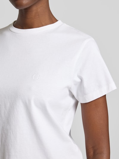 Frauenmodel trägt Regular Fit T-Shirt mit Logo-Stitching von Anine Bing aus reiner Baumwolle, Rundhalsausschnitt, Nahaufnahme Oberkörper.