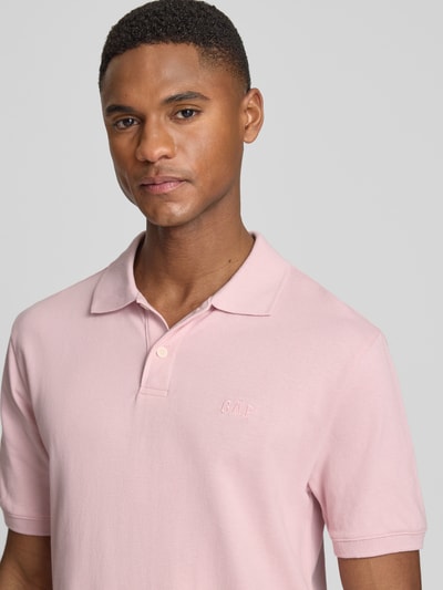 Männermodel trägt Slim Fit Poloshirt mit Label-Stitching von GAP in Rosa, Baumwoll-Elasthan-Mix, Nahaufnahme Oberkörper.