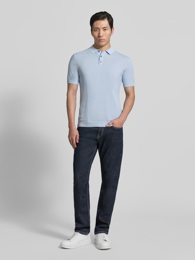 Männermodel trägt Slim Fit Poloshirt in Strick-Optik Modell 'Vanceo' von JOOP! Collection aus reiner Baumwolle, hellblau, Ganzkörperansicht von vorne.