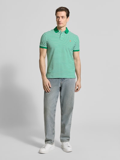Männermodel trägt Slim Fit Poloshirt aus reiner Baumwolle von Polo Ralph Lauren mit Two-Tone-Optik, gestreift, Logo-Detail, Piqué, Ganzkörperansicht von vorne.