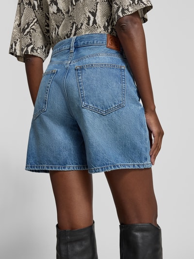 Frauenmodel trägt Jeansshorts aus reiner Baumwolle von Anine Bing in A-Linie mit 5-Pocket-Design und Kontrastnähten, Ganzkörperansicht Rückansicht.