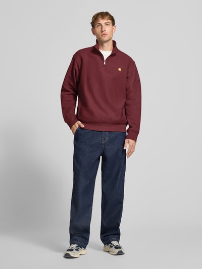 Männermodel trägt Relaxed Fit Sweatshirt aus elastischem Material-Mix von Carhartt Work In Progress, bordeaux, Label-Detail, Ganzkörperansicht von vorne.