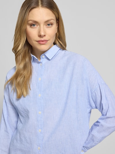 Kobiece model nosi Regular Fit Bluzę z mieszanki lnu i bawełny model 'LUCY' od 0039 Italy, kołnierzyk koszulowy, zbliżenie na górną część ciała. Kontext: bluzka damska od 0039 Italy, mieszanka lnu i bawełny, krój regular fit, model 'LUCY', kołnierzyk koszulowy, obniżone ramiona, długość tyłu w rozmiarze S: 67 cm, długość rękawów w rozmiarze S: 46 cm.