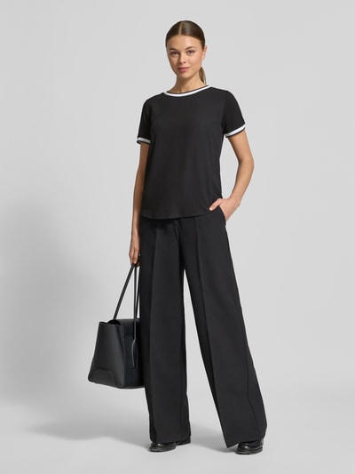 Modelka nosi Regular Fit T-Shirt aus Viskose-Mix von More & More, czarny, krój regular fit, dekolt okrągły, krótki rękaw, długość tyłu w rozmiarze 36: 57 cm, pełen widok z przodu.