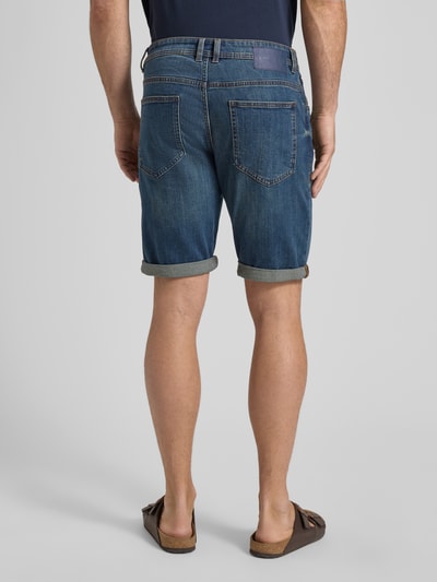 Männermodel trägt Regular Fit Jeans Bermudas aus Baumwoll-Mix von Tom Tailor in Denim-Optik mit Label-Patch, Ganzkörperansicht Rückansicht.