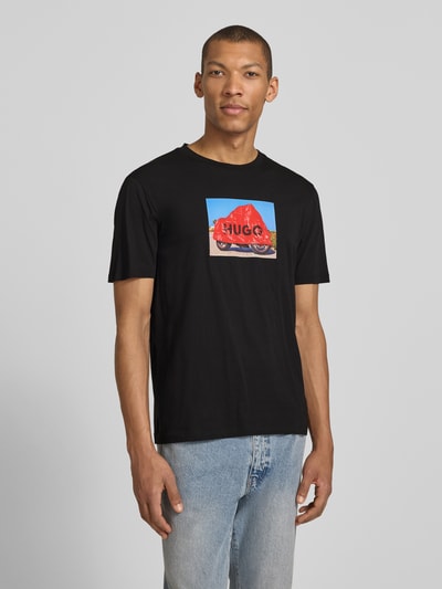 Männermodel trägt Relaxed Fit T-Shirt aus reiner Baumwolle Modell 'DOSTINO' von HUGO, unifarbenes Jersey mit Label Print, Rundhals, kurzarm, Ganzkörperansicht von vorne.