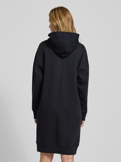 Kobiece modelka nosi Oversized Sweatkleid aus reiner Baumwolle von Marc O'Polo, jednolity kolor, krój oversized, długość midi, aplikacja z wyhaftowanym logo, napis z logo, długi rękaw zakończony prążkowanym ściągaczem, dzianina dresowa, bawełna, pełna sylwetka z tyłu