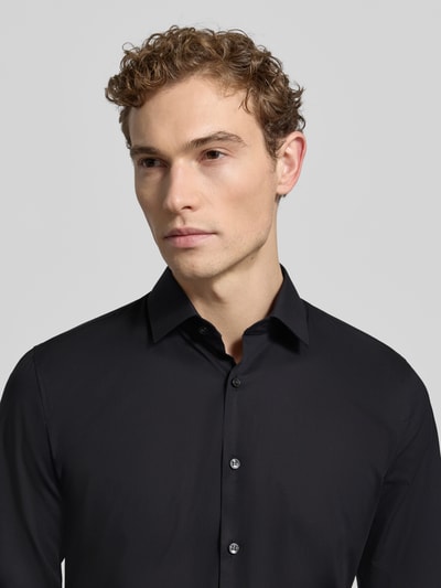 Männermodel trägt schwarzes Super Slim Fit Businesshemd mit Kentkragen und Knopfleiste, Baumwoll-Mix mit Stretch-Anteil, OLYMP No. Six, Modell 'URBAN KENT', Nahaufnahme Oberkörper
