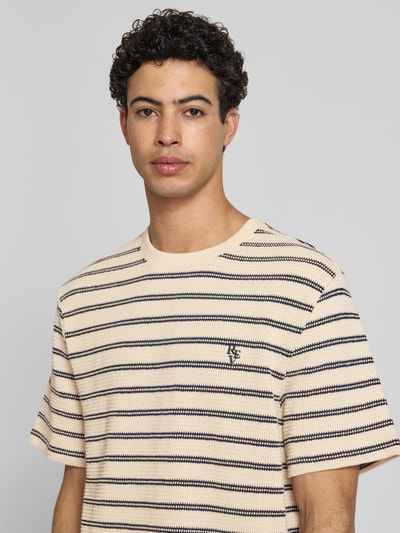 Männermodel trägt Strukturiertes T-Shirt mit Logostickerei auf der Brust von REVIEW, Beige mit schwarzen Streifen, Reine Baumwolle, Nahaufnahme Oberkörper.