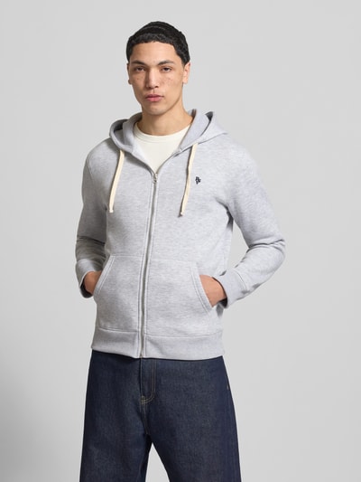 Männermodel trägt Slim Fit Sweatjacke mit Label-Stitching von REVIEW in hellgrau mit Känguru-Tasche, Ganzkörperansicht von vorne.