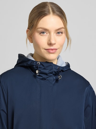Frauenmodel trägt Mantel mit Pattentaschen von WHITE LABEL in Dunkelblau mit Kapuze, elastischen Abschlüssen, Nahaufnahme Oberkörper.
