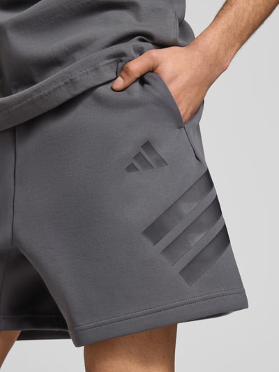 Männermodel trägt Regular Fit Sweatshorts mit Baumwoll-Anteil von adidas Sportswear, Optik: Unifarben, Logo-Print, Sweat, Nahaufnahme Oberschenkel.