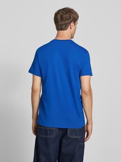 Männermodel trägt Slim Fit T-Shirt aus reiner Baumwolle von Tommy Jeans in kräftigem Blau, glatte Oberfläche, Ganzkörperansicht Rückansicht.