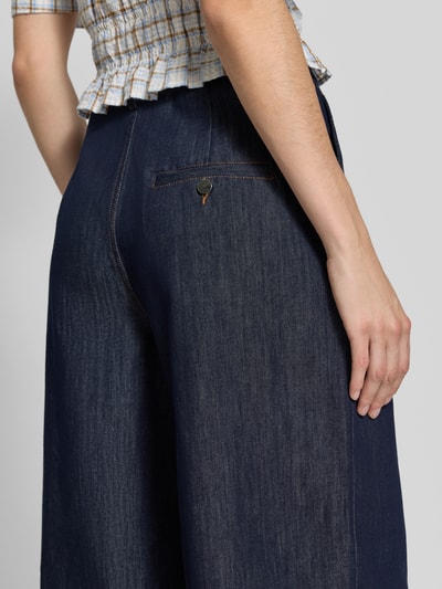 Frauenmodel trägt Wide Fit Jorts aus reiner Baumwolle von Oiu, dunkles Denim mit Bundfalten und Knopfverschluss, Nahaufnahme Rückansicht.