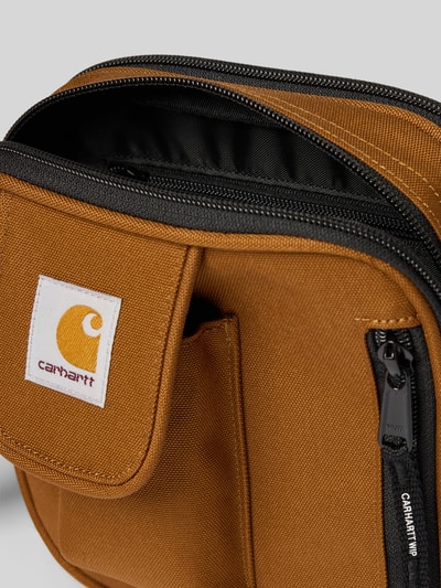 Productfoto, Crossbody Bag met logo-patch van Carhartt Work In Progress in bruin met zwarte ritssluiting, hoofdvak met ritssluiting, logopatch, verstelbare en afneembare schouderband, breedte 17 cm, lengte 18 cm, diepte 6 cm, bandlengte 80 cm