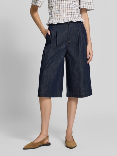 Frauenmodel trägt Wide Fit Jorts aus reiner Baumwolle von Oiu, Bundfalten, dunkelblau, mittlere Struktur, Nahaufnahme Oberschenkel bis Knie.