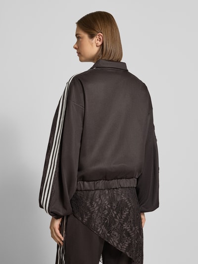 Männermodel trägt Oversized Sweatjacke aus Baumwoll-Mix Modell 'LACE OVERSIZED' von adidas Originals in Schwarz mit weißen Streifen, Strukturmix, Ganzkörperansicht Rückansicht.