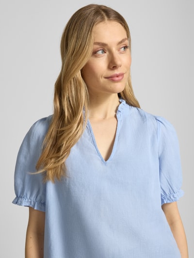 Modelka nosi Blusenshirt aus Leinen-Baumwoll-Mix Modell 'Odesa' von Neo Noir, damska bluzka z mieszanki lnu i bawełny, krój regular fit, dekolt w serek, długość tyłu w rozmiarze 36: 58 cm, długość rękawów w rozmiarze 36: 31 cm; jasnoniebieski kolor, tekstura lekko matowa, krótki rękaw; zbliżenie na górną część sylwetki, przód.