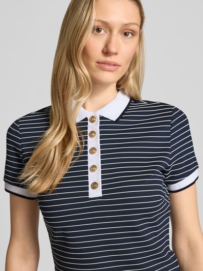 Modelka kobieca nosi knielanges Polokleid mit Polokragen Modell 'ALPHONSINE' von Guess, granatowe paski, krój slim fit, widok z przodu, zbliżenie na górną część. Viskose-Mix z dodatkiem stretchu, długość do kolan, krótkie rękawy, krótka listwa guzikowa, długość tyłu w rozmiarze S: 93 cm, szerokość w rozmiarze S: 40 cm, długość rękawa w rozmiarze S: 18 cm.