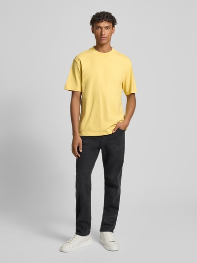 Männermodel trägt Regular Fit T-Shirt aus reiner Baumwolle Modell 'DAPOLINO' von HUGO in Gelb, unifarben, Label-Schriftzug, Ganzkörperansicht von vorne.