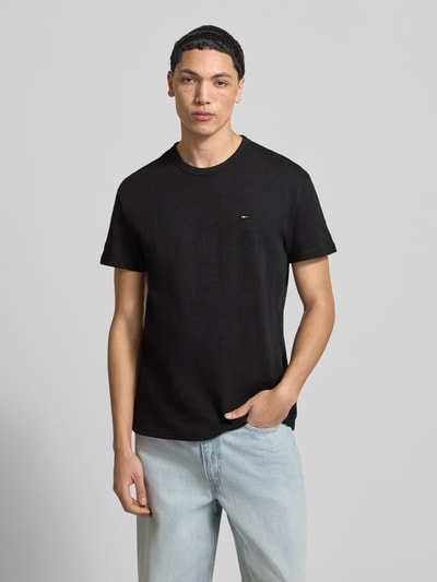 Männermodel trägt Regular Fit T-Shirt aus reiner Baumwolle von Tommy Jeans, Optik: Unifarben, Logo-Detail, Jersey, Nahaufnahme Oberkörper.