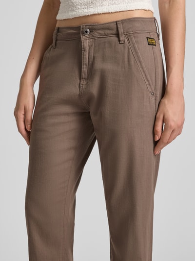 Vrouwenmodel draagt Straight Fit Chino uit puur katoen van g-star, effen look, steekzakken, labeldetail, gevlamd garen, mid waist, knoop- en ritssluiting, paspelzakken, detailopname bovenlichaam
