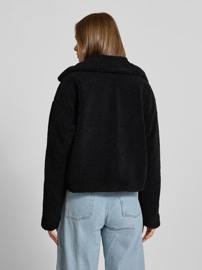 Frauenmodel trägt Cropped Jacke aus Teddyfell Modell 'Nati' von NOISY MAY®, schwarz, weiche Textur, lockerer Schnitt, Ganzkörperansicht Rückansicht.