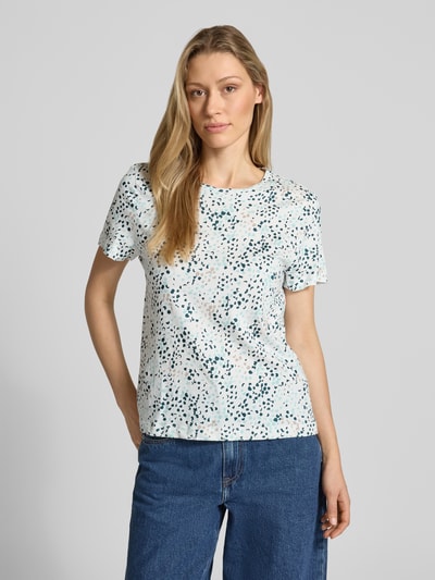 Frauenmodel trägt Regular Fit T-Shirt aus reiner Baumwolle von Tom Tailor mit Optik:Allover-Muster, abstrakt gepunktet, Rundhals, Kurzarm, Jersey, Logo-Patch, in hellen Farben mit blauen und schwarzen Punkten, glatte Textur, Ganzkörperansicht von vorne.