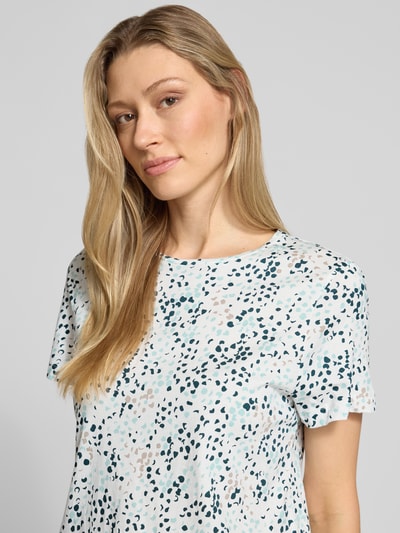 Frauenmodel trägt Regular Fit T-Shirt aus reiner Baumwolle von Tom Tailor mit Optik:Allover-Muster, abstrakt gepunktet, Logo-Patch, Rundhals, Kurzarm, Materialverarbeitung: Jersey, Nahaufnahme Oberkörper.