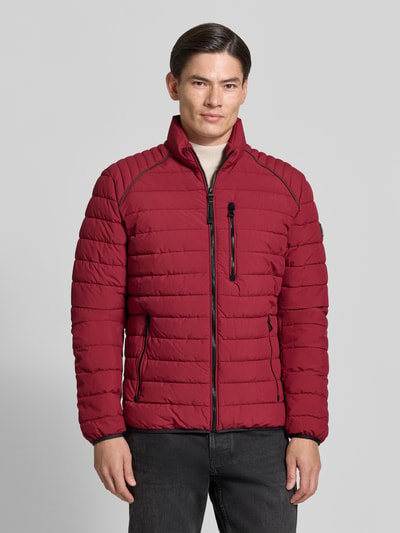 Mannenmodel draagt Steppjacke met Stehkragen und Reißverschlusstaschen van LERROS in rood, regular fit, ritszakken, Ganzkörperansicht van voren. Ruglengte maat M 69 cm, schouderbreedte 46 cm, borstwijdte 60 cm, mouwlengte 69 cm.