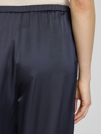 Frauenmodel trägt Wide Fit Hose mit elastischem Bund von Comma, Material-Mix mit Viskose-Anteil, dunkelblauer Glanz, Detailaufnahme Rückansicht.
