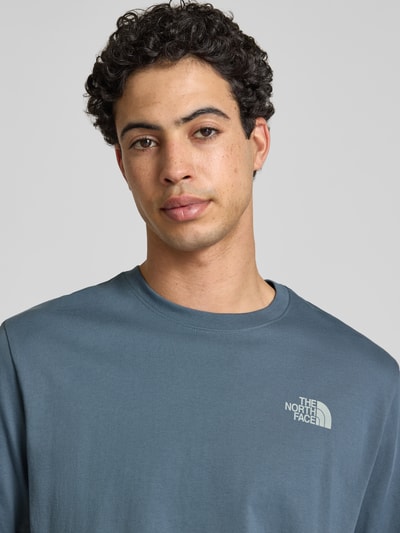 Männermodel trägt Relaxed Fit T-Shirt mit Logo-Print von The North Face in Blau, reine Baumwolle, Rundhalsausschnitt, Nahaufnahme Oberkörper.