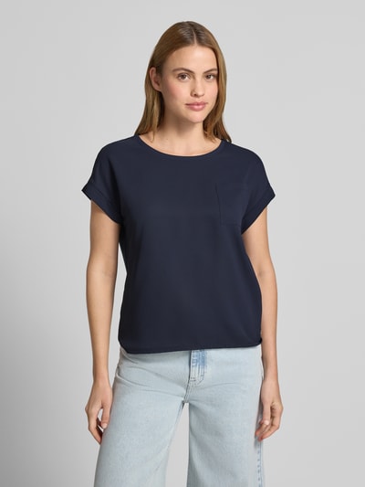 Frauenmodel trägt Blusenshirt mit verlängertem Rücken und Brusttasche von monari in Dunkelblau, Gerader-Schnitt, Rundhalsausschnitt, Ärmel mit Aufschlag, Brusttasche, Label-Detail, Rückenlänge bei Größe 36: 54 cm, Ärmellänge bei Größe 36: 3 cm, glatte Textur, Ganzkörperansicht von vorne.