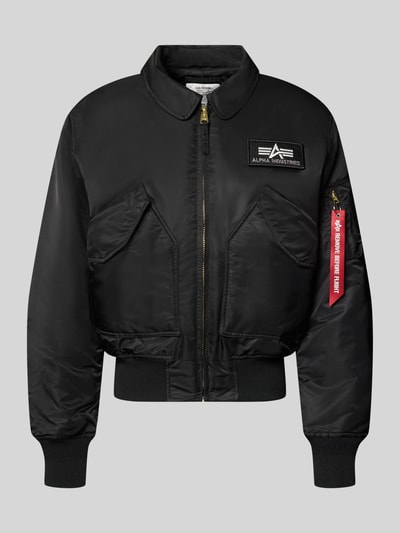 Produktfoto, schwarze Bomberjacke mit seitlichen Pattentaschen und Label-Patch von Alpha Industries, glatte Oberfläche, goldfarbener Reißverschluss, Rippenbündchen, Kentkragen, Regular Fit, Reißverschlusstasche am Ärmel mit Label-Detail, minimalistisches Design, Produktname: Bomberjacke mit seitlichen Pattentaschen und Label-Patch von Alpha Industries, Rückenlänge 62 cm, Schulterbreite 50 cm, Brustweite 61 cm, Ärmellänge 67 cm