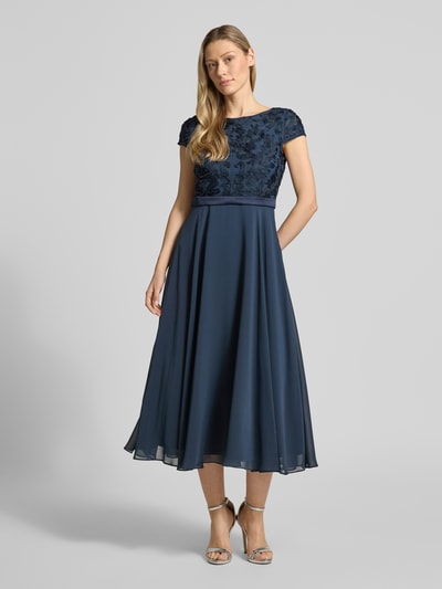 Kobiece model prezentuje Cocktailkleid mit Stitchings und Perlen von Christian Berg Cocktail, mieszanka materiałów z dodatkiem streczu, sukienka koktajlowa linia a, sukienka midi, hafty, perły, okrągły dekolt, długość tyłu w rozmiarze 36: 124 cm, szerokość w rozmiarze 36: 45 cm, granatowy kolor, całkowity widok z przodu.