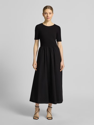 Vrouwenmodel draagt Midikleid in Falten-Optik van Christian Berg Woman Selection, zwarte katoenmix, getailleerde pasvorm, ronde hals, plooien, met korte mouwen, ruglengte maat 36: 125 cm, borstwijdte 38 cm, mouwlengte 24 cm. Ganzkörperaanzicht van voren.