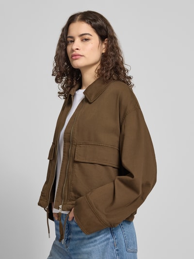 Modelka nosi Regular Fit Jeansjacke aus Baumwoll-Mix von Marc O'Polo Denim w kolorze brązowym, mieszanka bawełny, z długim rękawem, wykładanym kołnierzem, zamkiem błyskawicznym, naszywką z logo oraz kieszeniami na piersi, wykończenie: denim, efekt: jednolity kolor, widok z przodu, ujęcie w półprofilu.