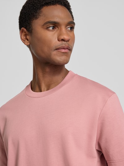 Męski model nosi t-shirt z bawełny ekologicznej, model 'Achilleas' od JOOP! kolekcja, krój regular fit, okrągły dekolt, detal z logo; zbliżenie na górną część ciała.