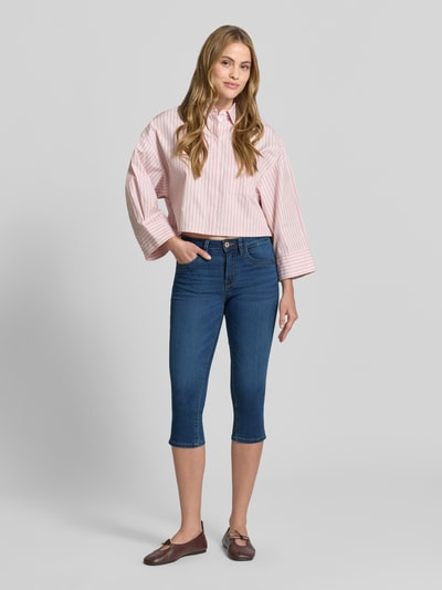 Frauenmodel trägt Slim Fit Caprijeans aus Baumwoll-Mix von Tom Tailor in klassischer Denim-Optik mit 5-Pocket-Design, Ganzkörperansicht von vorne.