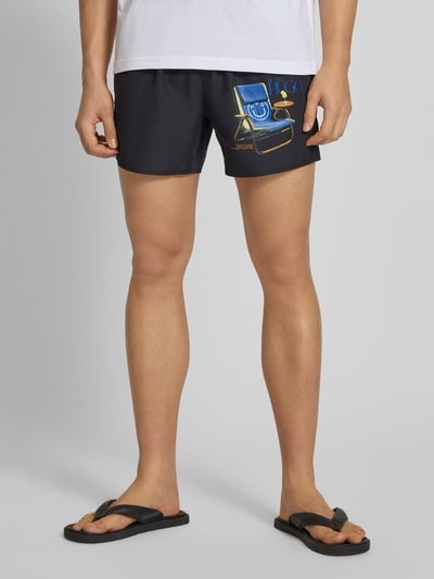 Mannenmodel draagt Badeshorts met motiefprint van Hugo Blue, look: effen kleuren, tunnelkoord, elastische boord, steekzakken, popeline, detailopname onderlichaam