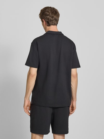 Männermodel trägt Regular Fit T-Shirt mit Logo-Stitching von PUMA PERFORMANCE in Schwarz mit Strukturmuster, Baumwoll-Mix, Rückenlänge 74 cm, Ganzkörperansicht Rückansicht.