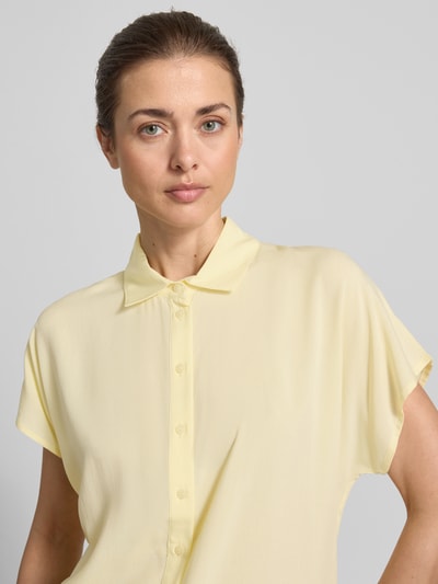 Frauenmodel trägt Regular Fit Bluse aus Viskose von Christian Berg Woman in zartem Gelb mit Hemdblusenkragen und Knopfleiste, Nahaufnahme Oberkörper. Rückenlänge 64 cm, Ärmellänge 15 cm bei Größe 36.