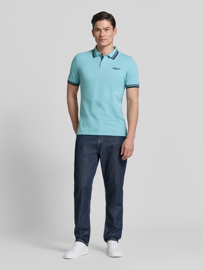 Männermodel trägt Regular Fit Poloshirt aus Baumwoll-Mix von s.Oliver RED LABEL, Optik: Unifarben, Label-Print, Piqué, Ganzkörperansicht von vorne.