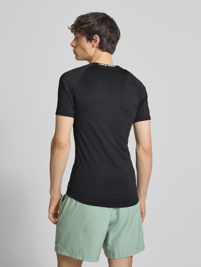 Männermodel trägt T-Shirt mit Logo-Print und Rundhalsausschnitt von NIKE TRAINING, Slim-Fit, Raglanärmel, Rückenlänge 72 cm, Ganzkörperansicht Rückansicht.