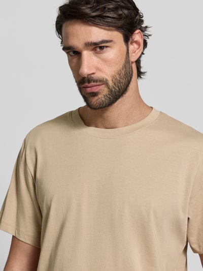 Męski model ma na sobie Regular Fit T-Shirt aus reiner Baumwolle Modell 'ASPAN' von SELECTED HOMME, jednolity beżowy kolor, krótki rękaw, okrągły dekolt, jersey, optyka gładka, materiał bawełniany, półzbliżenie na górną część ciała.