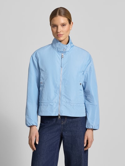 Frauenmodel trägt Jacke mit Zweiwege-Reißverschluss und Stehkragen von Fuchs Schmitt, hellblau, Gerader-Schnitt, glatte Textur, Eingrifftaschen mit Druckknopfverschluss, elastische Ärmelabschlüsse, Rückenlänge 61 cm bei Größe 36, Schulterbreite 49 cm, Brustweite 56 cm, Ärmellänge 56 cm, Ganzkörperansicht von vorne.