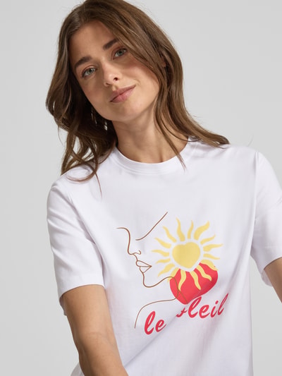 Frauenmodel trägt Damen T-Shirt mit Stitching Modell 'NORA' von Vila aus Baumwoll-Elasthan-Mix, Regular-Fit, Rundhalsausschnitt, Vorderseite mit Grafikprint, Nahaufnahme Oberkörper.