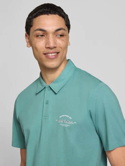 Männermodel trägt Poloshirt mit Label-Print Modell 'BRANDON' von Jack & Jones, Reine Baumwolle, Regular-Fit, Polokragen, Knopfleiste, Nahaufnahme Oberkörper.
