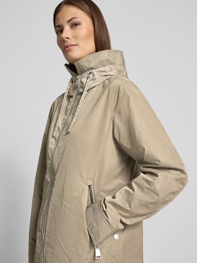 Vrouwenmodel draagt Jacke mit Zweiwege-Reißverschluss van Fuchs Schmitt in regular fit, beige kleur, zichtbare ritszakken en opstaande kraag, nahaufnahme bovenlichaam.